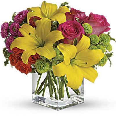 Splash into spring! Sun-bright yellow, hot pink and orange blooms add up to a sensational and oh-so-stylish spring & summer floral arrangement for any occasion.
Hot pink and orange roses are mixed with yellow asiatic lilies, hot pink matsumoto asters and lime green button spray chrysanthemums in a clear glass cube vase.